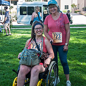 Woman in a wheelchair with a woman standing behind her smiling, at the Manitou Walk